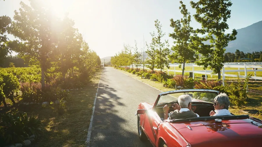 Couple, convertible and driving road trip or travel journey to California vineyard, adventure or transportation. People, nature and tourism holiday for explore together in retirement, morning or love