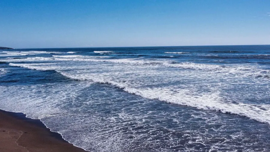 a drone shot of foamy waves crashing the goat rock