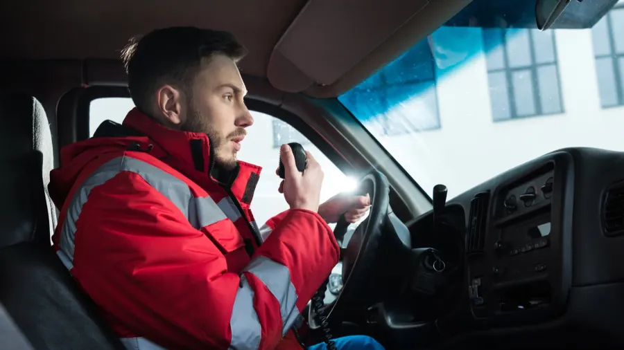 young handsome male paramedic talking by portable radio